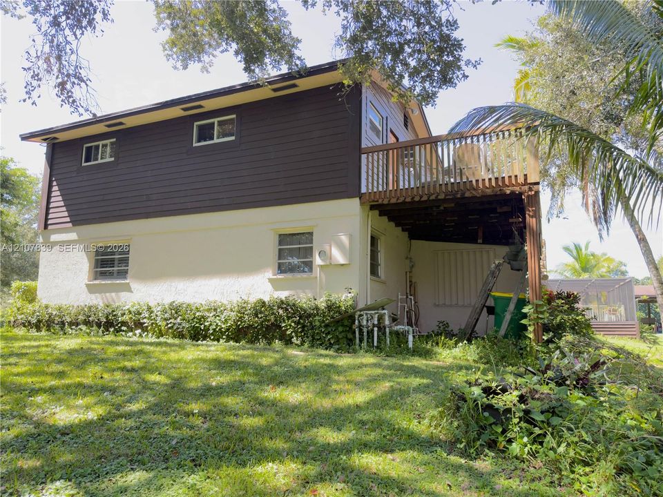 Two-story exterior featuring a mix of horizontal wood-finish siding and stucco finish, elevated wooden deck, and sliding glass door