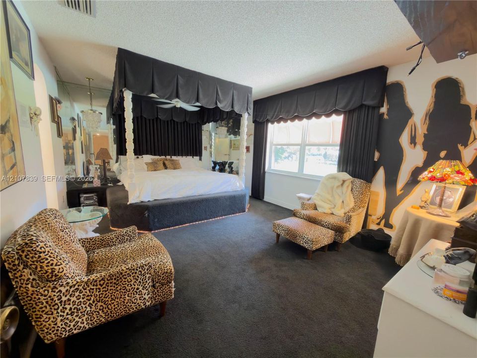 Spacious room featuring floor-to-ceiling mirrored walls, a custom built-in elevated platform, and a large multi-pane window with custom valance