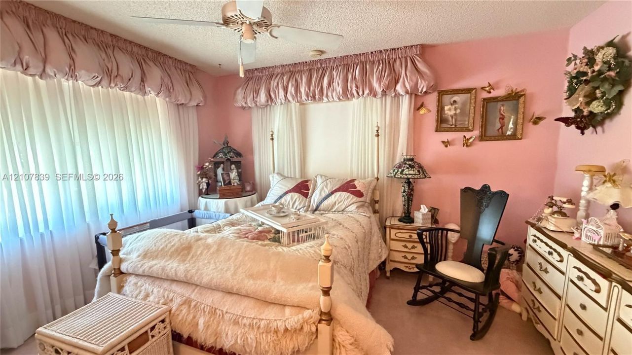 Bedroom featuring large windows with ceiling-mounted fabric valances, wall-to-wall carpeting, and a ceiling fan with integrated lighting