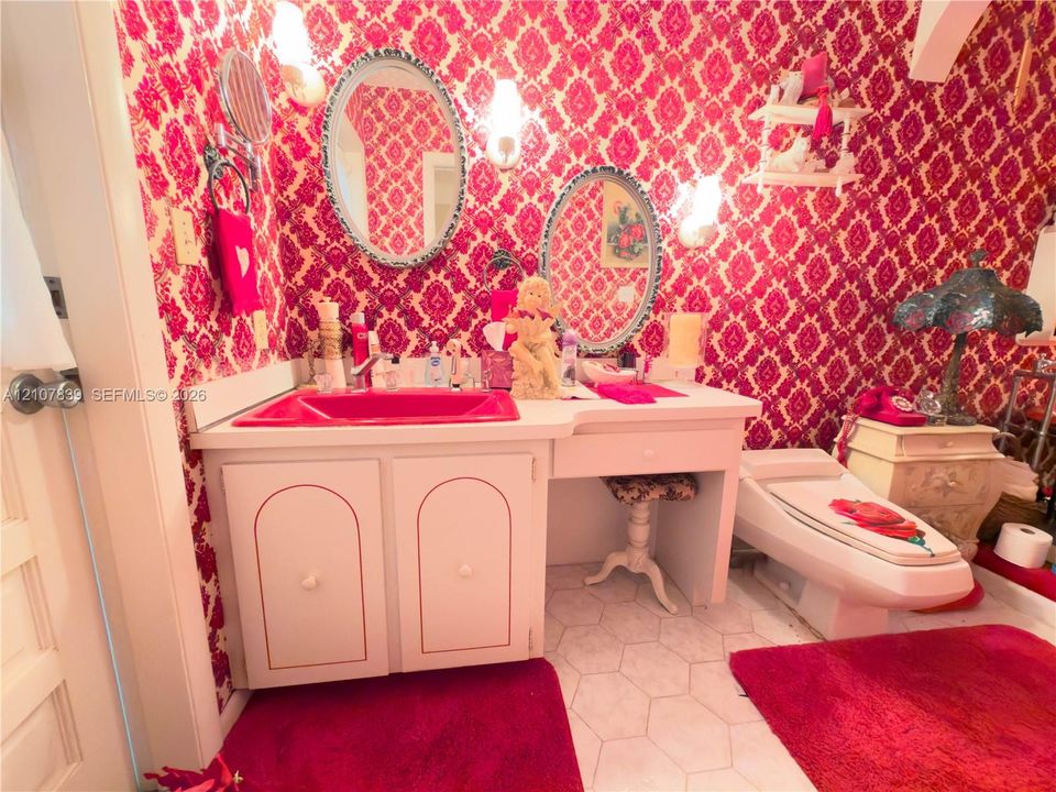 Custom vanity featuring a bright sink basin, dual oval mirrors with decorative frames, built-in cabinetry, and hexagonal tile flooring