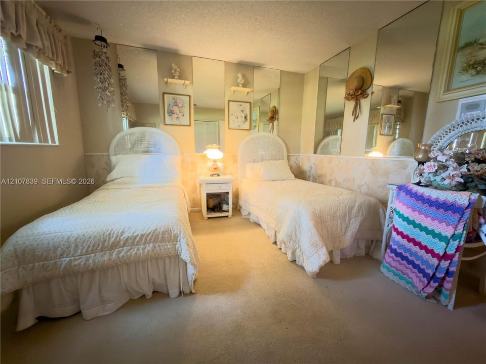 Room featuring wall-to-wall carpeting, floor-to-ceiling wall mirror panels, and patterned wainscoting