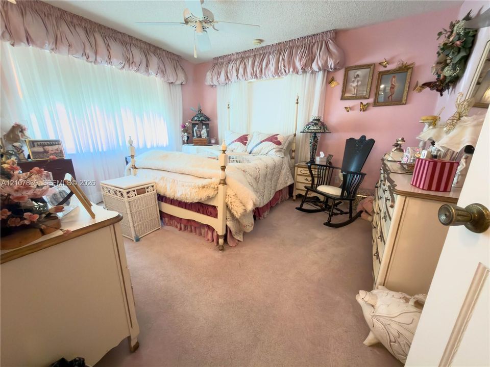 Bedroom featuring carpeted flooring, a ceiling fan with light kit, and large windows with floor-to-ceiling drapery