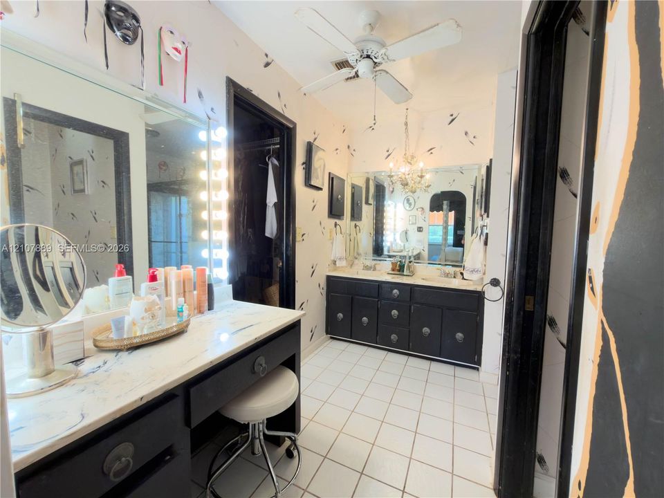 Double vanity with dark cabinetry, white countertops, ceramic tile flooring, built-in vanity station, and ceiling-mounted lighting