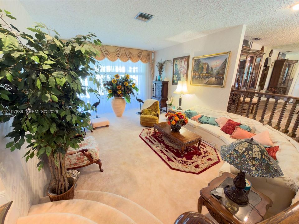 Large floor-to-ceiling windows featuring a fabric valance, decorative wooden balustrade, and carpeted flooring