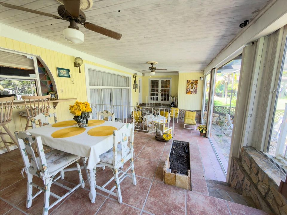 Covered patio featuring large-format terra-cotta tile flooring, dual ceiling fans, a built-in planter, and expansive glass sliding doors