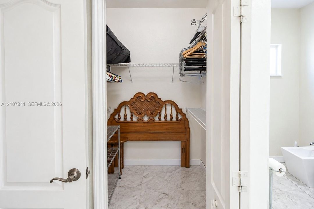 Walk-in closet featuring stone-finish tile flooring and multi-tier wire shelving