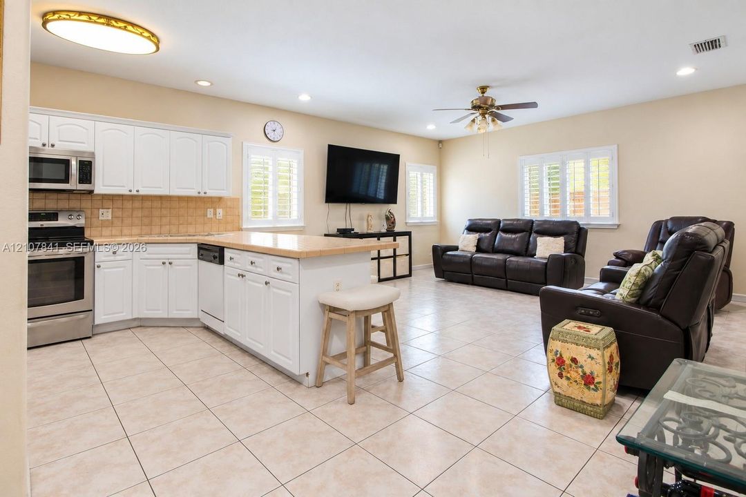Open-concept interior featuring white cabinetry, a center island, ceramic tile flooring, plantation shutters, and recessed lighting