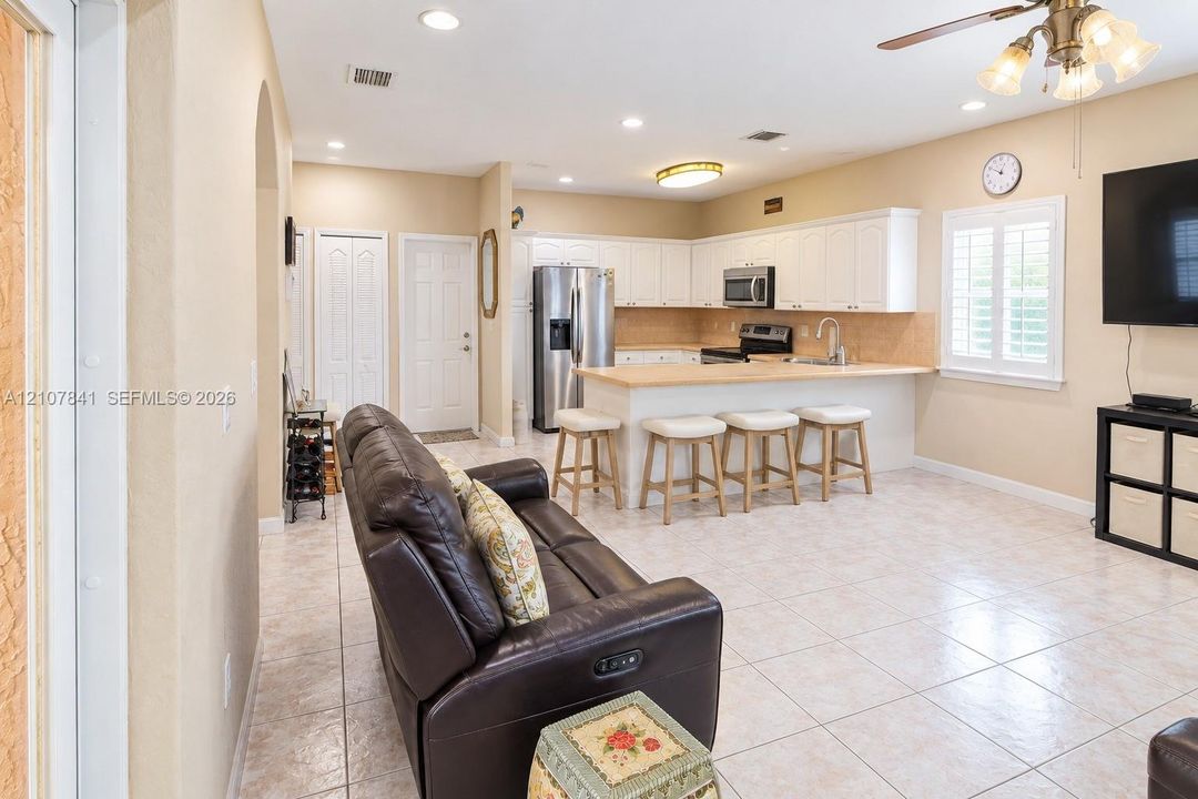Open-concept kitchen featuring white cabinetry, a breakfast bar, recessed lighting, and tile flooring