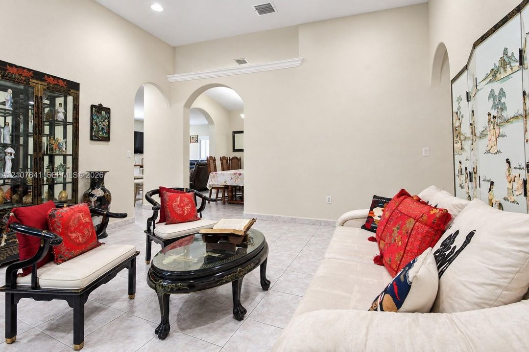 High-ceiling living area featuring neutral tile flooring, recessed lighting, and architectural archways