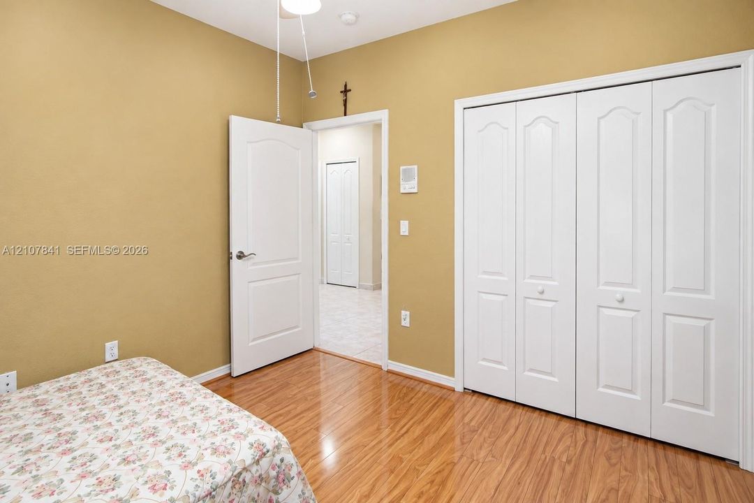 Interior room featuring wood-finish flooring, white paneled interior doors, and a four-panel bi-fold closet