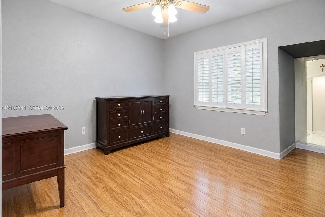 Wood-finish flooring, neutral wall tones, plantation shutters, and a ceiling fan with integrated lighting