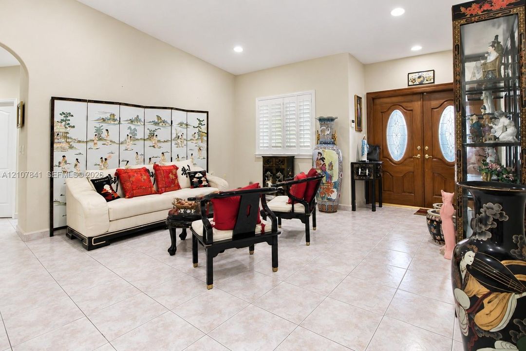 Vaulted ceiling featuring recessed lighting, double-door entryway with oval glass inserts, and light-toned tile flooring throughout