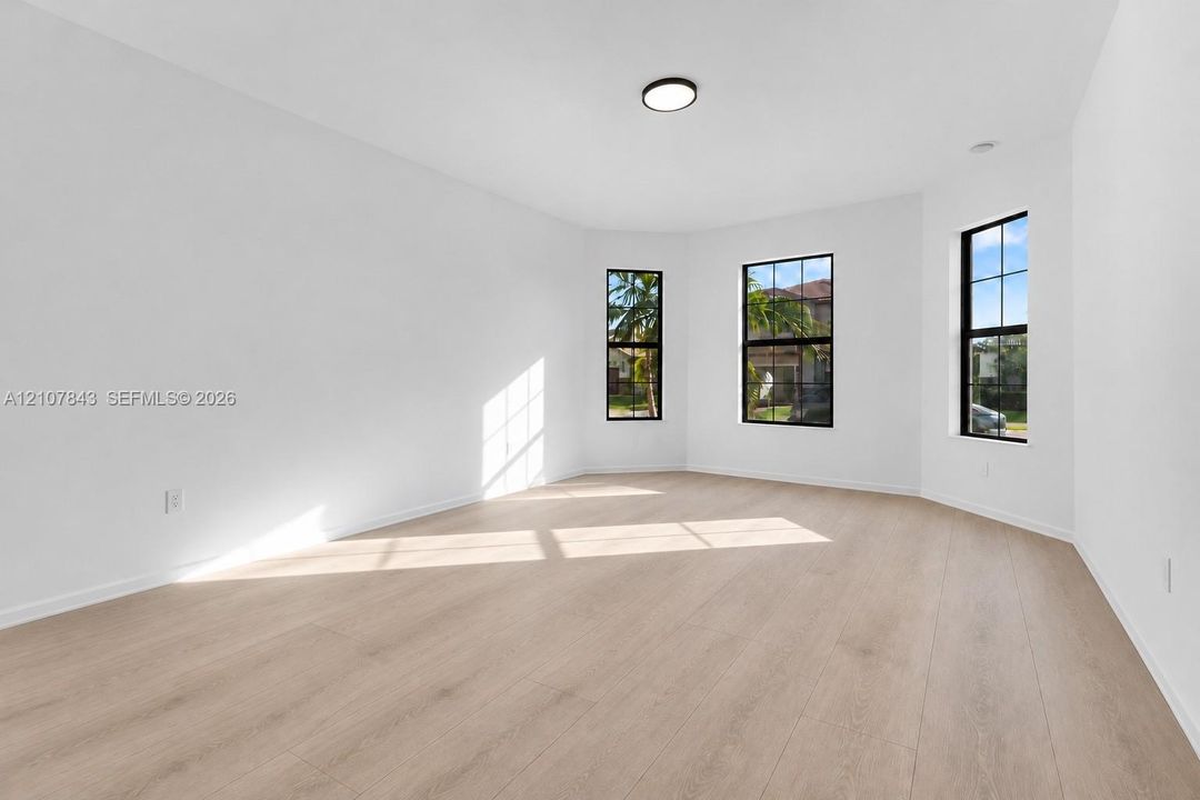 Neutral interior space featuring wood-finish flooring, a bay window configuration, and black-framed windows