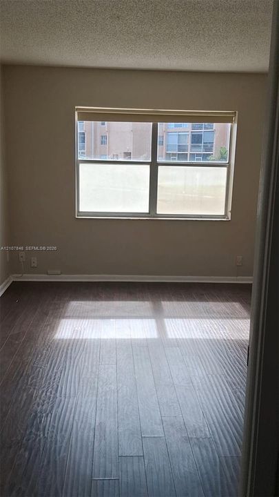 Wood-finish flooring and a single-pane horizontal window featuring a neutral roller shade