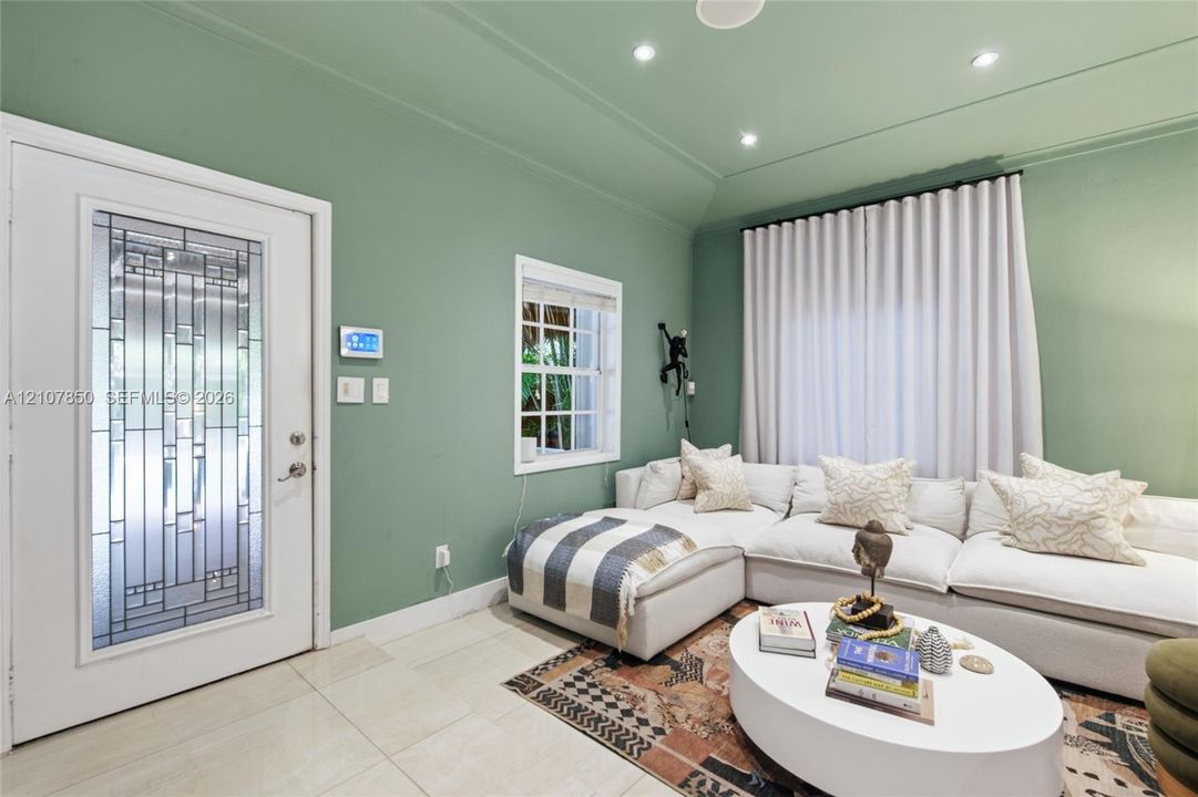 Entry area featuring a glass-inset door with geometric detailing, recessed ceiling lighting, tray ceiling architecture, large-format tile flooring, and a multi-pane window
