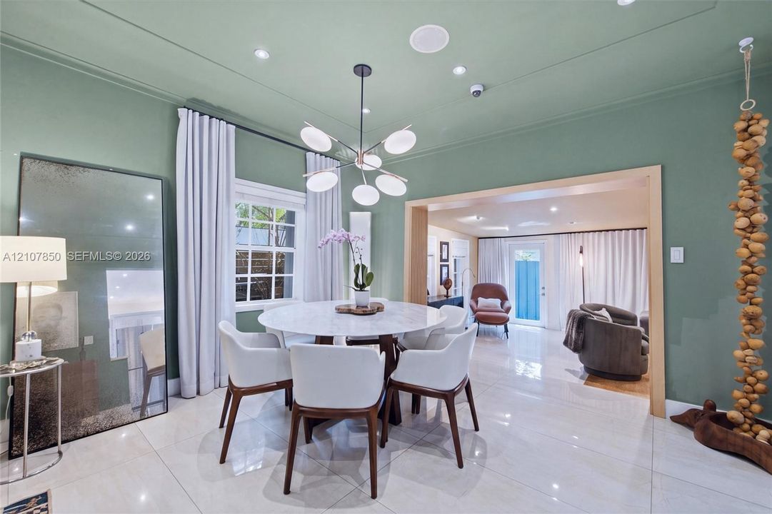 Polished tile flooring, modern multi-arm chandelier with glass globe shades, recessed ceiling lighting, and custom wide-cased door frame