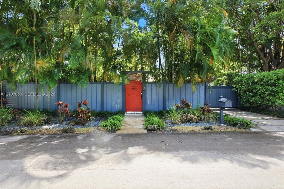 Solid-panel privacy fencing, gated pedestrian entry, concrete paver walkway, and mature landscaping