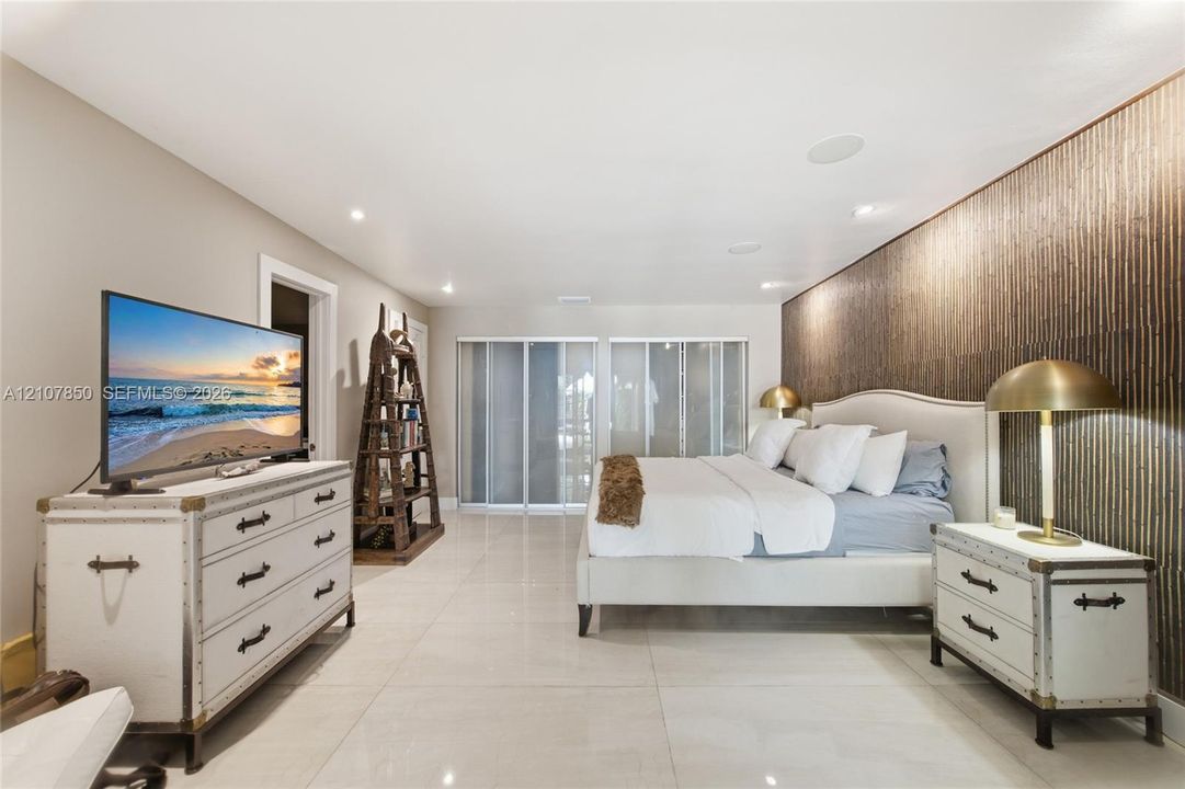Large-format tile flooring, textured wall covering, recessed ceiling lighting, and sliding glass closet doors
