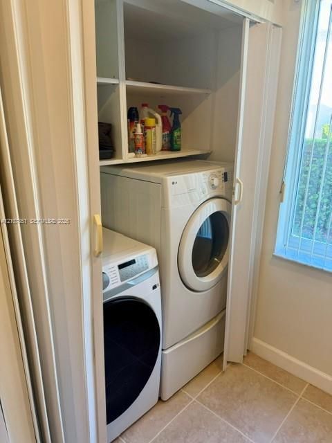 Laundry area featuring built-in shelving, tile flooring, and bi-fold closet doors