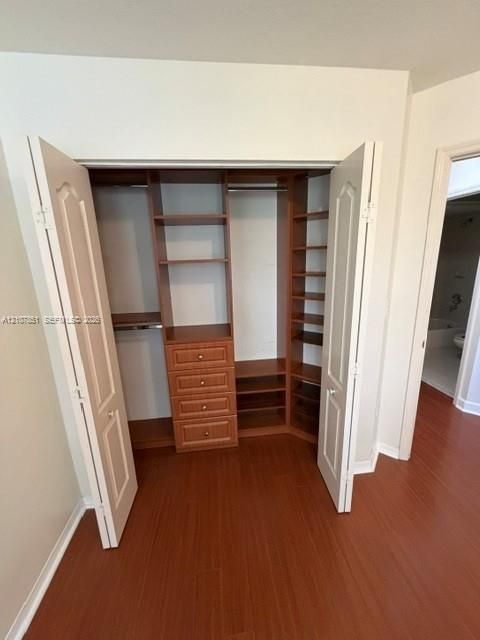 Built-in closet organizer featuring wood-finish shelving, integrated storage drawers with hardware, and hanging rods