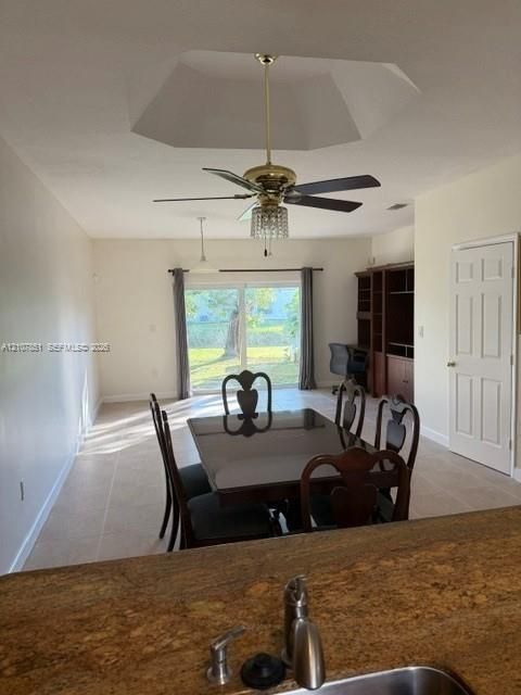 Tray ceiling with integrated lighting, built-in shelving unit, sliding glass doors, and tile flooring