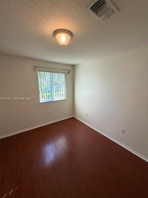 Interior room featuring wood-finish flooring, a single-pane window with vertical blinds, and a flush-mount ceiling light fixture