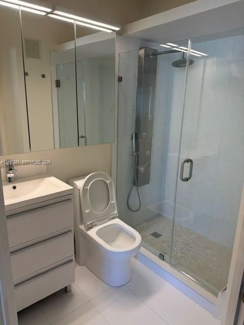 Modern bathroom featuring a three-drawer vanity with integrated sink, floor-to-ceiling mirrored medicine cabinet, glass-enclosed walk-in shower with pebble-stone flooring, and a stainless steel shower panel system