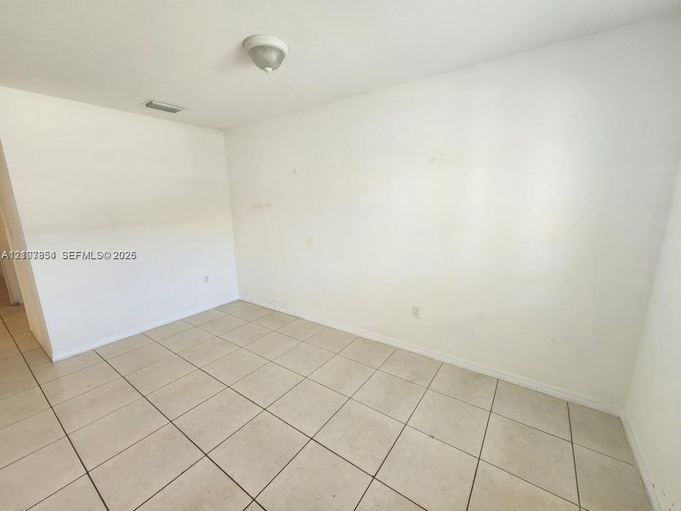 Neutral-toned ceramic tile flooring throughout, featuring a flush-mount ceiling light fixture