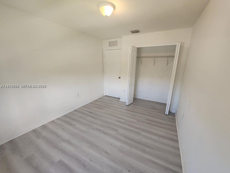 Neutral-toned wood-finish flooring, ceiling-mounted light fixture, and closet with bifold doors and built-in shelving