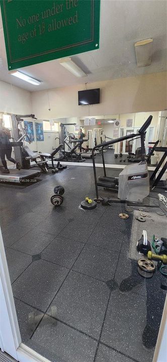 Fitness facility featuring rubberized flooring and wall-to-wall mirrors