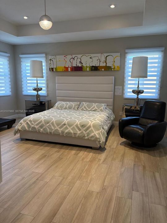 Tray ceiling featuring recessed lighting, wood-finish flooring, and dual windows with motorized roller shades