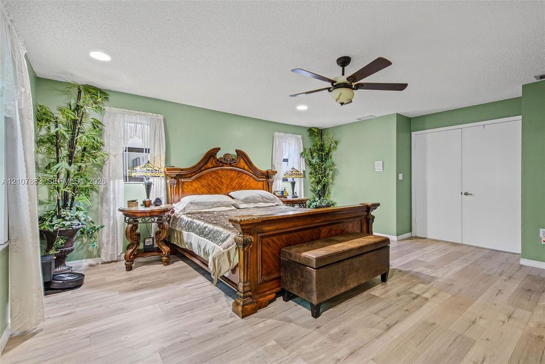 Wood-finish flooring, ceiling fan with integrated lighting, recessed lighting, and double-door closet