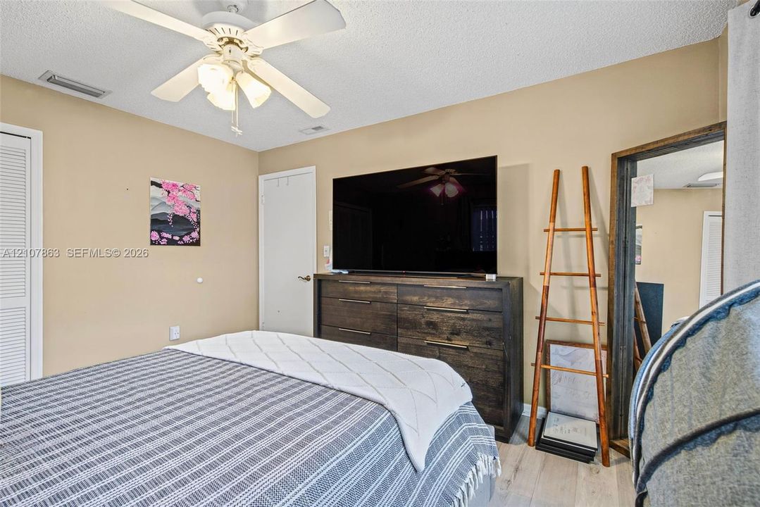 Wood-finish flooring, ceiling fan with integrated light fixture, and louvered closet doors
