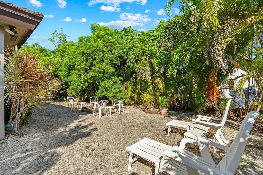 Private backyard featuring crushed stone ground cover and mature tropical landscaping