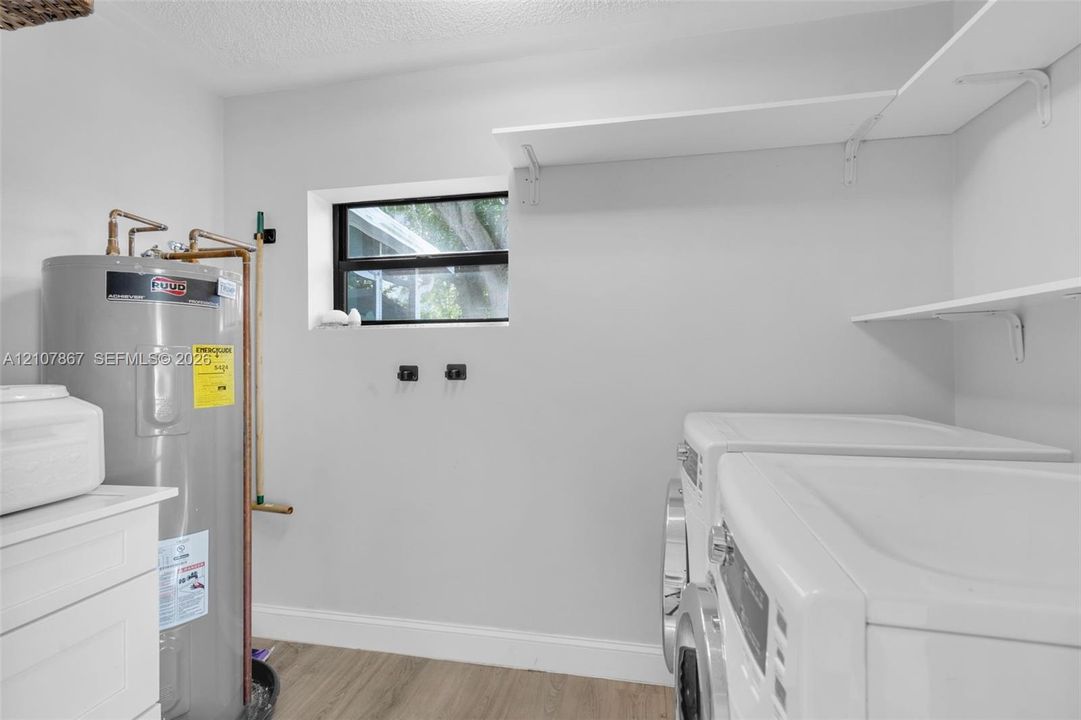 Utility space featuring wood-finish flooring, white shelving, and a window