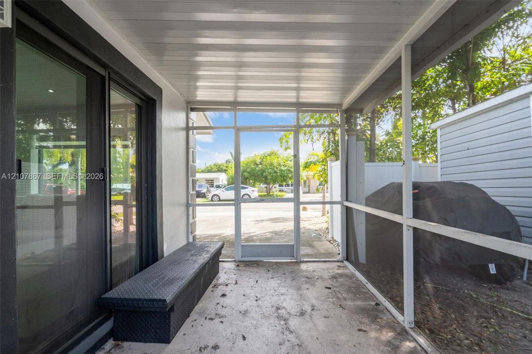 Enclosed screened porch featuring a concrete floor, aluminum ceiling panels, and sliding glass entry doors
