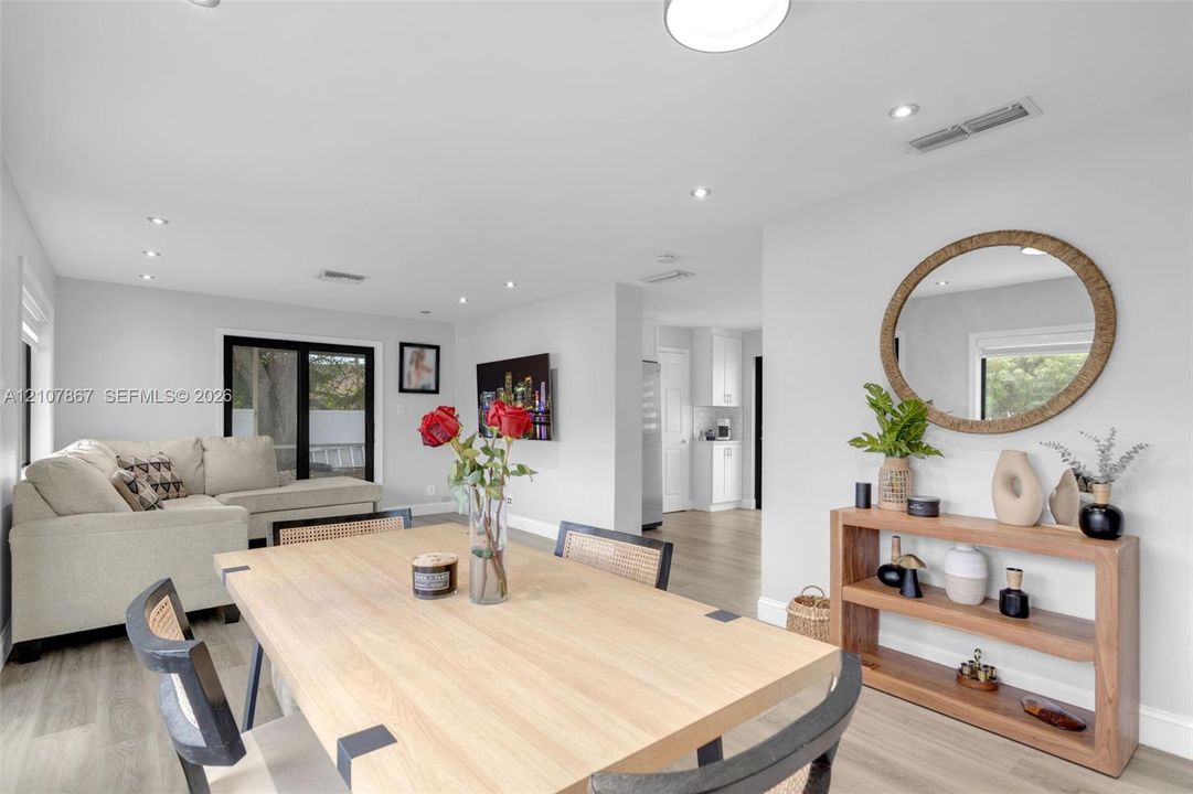 Open-concept interior featuring light wood-finish flooring, recessed lighting, and black-framed sliding glass doors