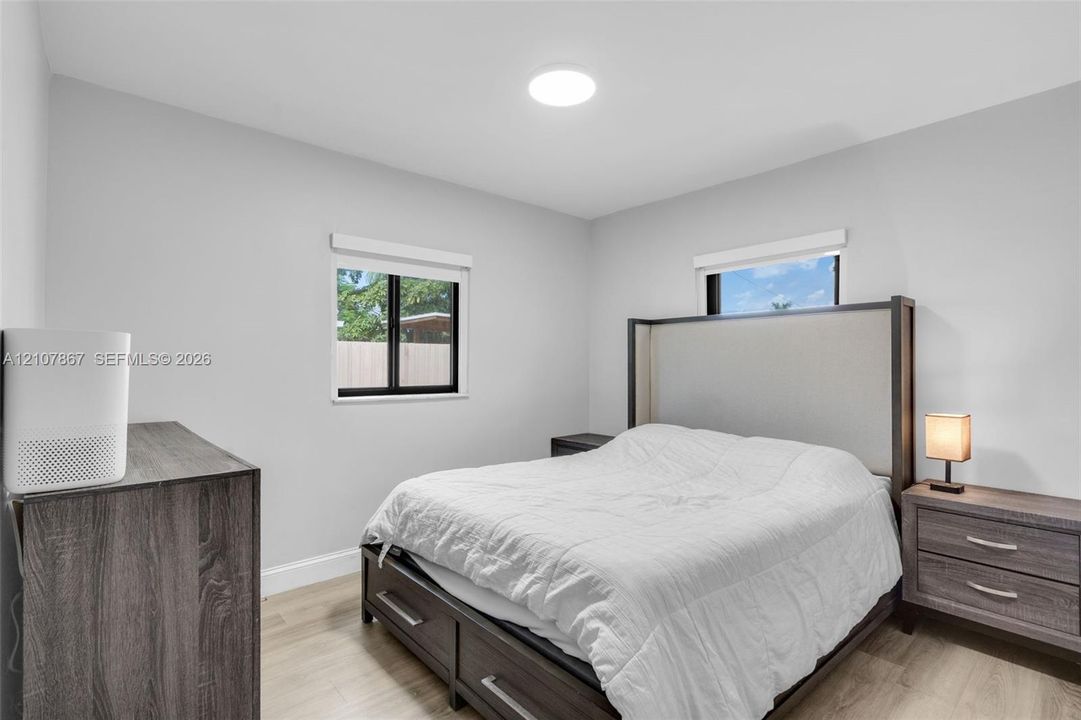 Neutral wall tones, wood-finish flooring, and black-framed windows accented by recessed ceiling lighting