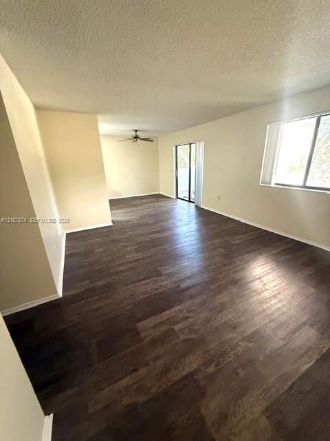 Open-concept living space featuring wood-finish flooring, a ceiling fan, and sliding glass doors