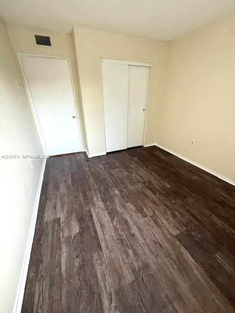 Room featuring wood-finish flooring, neutral wall paint, and a sliding-door closet