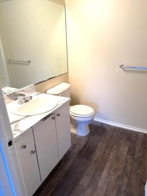 Vanity featuring a white countertop with grey veining, integrated oval sink, wood-finish flooring, full-width mirror, and chrome fixtures
