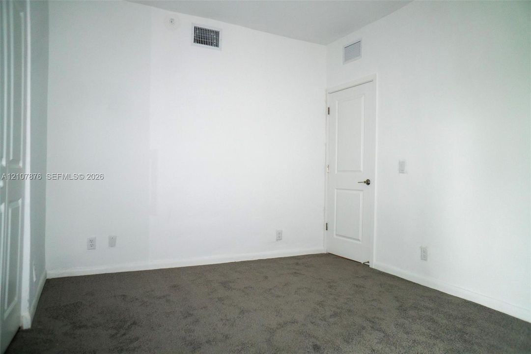 Neutral-toned carpeted flooring, two-panel interior door, and smooth walls