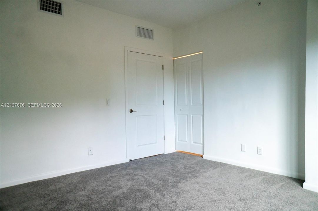 Neutral-toned wall paint, gray wall-to-wall carpeting, and white interior doors with satin nickel hardware