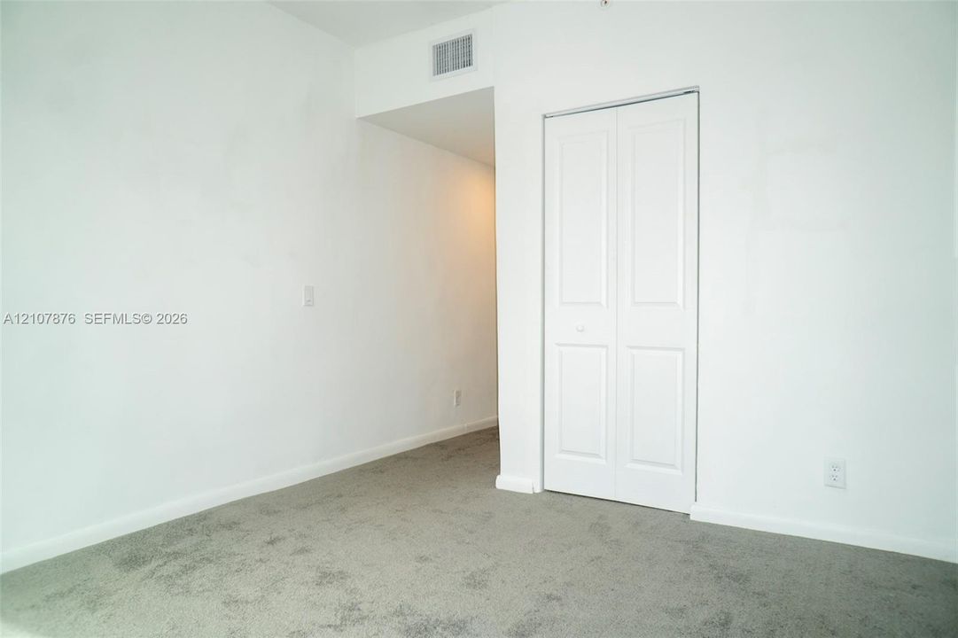 Neutral-toned carpeting and a closet with white paneled bi-fold doors