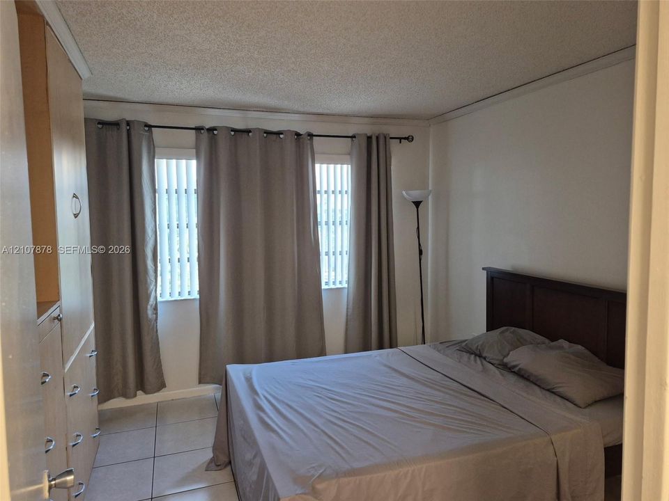 Tile flooring, built-in light-tone wood cabinetry, and dual vertical window panels with integrated blinds