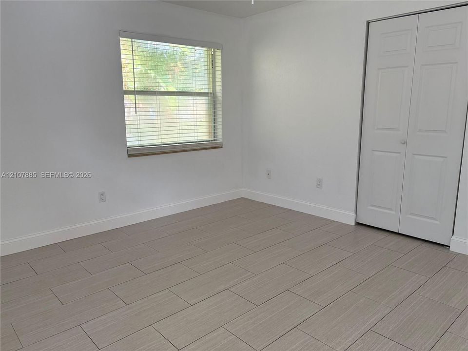 Neutral-toned tile flooring, light-filled interior, and dual-panel closet doors