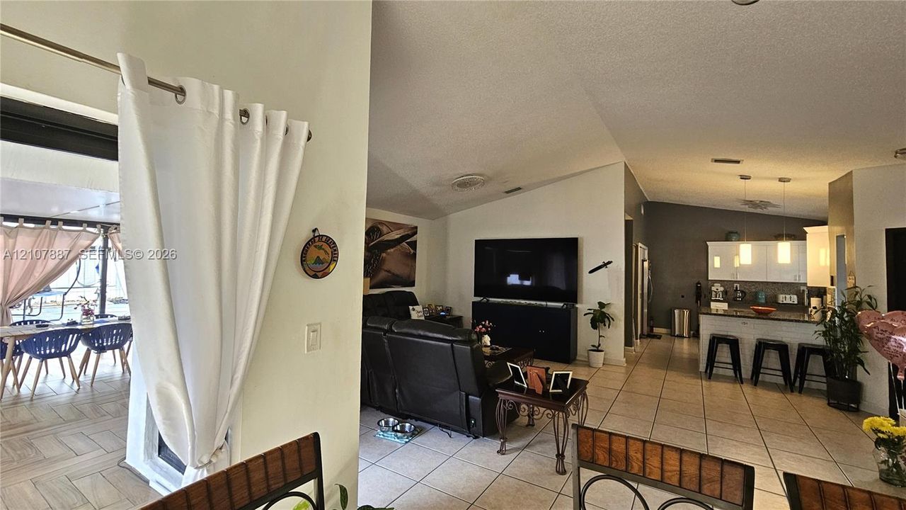 Open-concept interior featuring vaulted ceilings, tile flooring, and a kitchen island with pendant lighting
