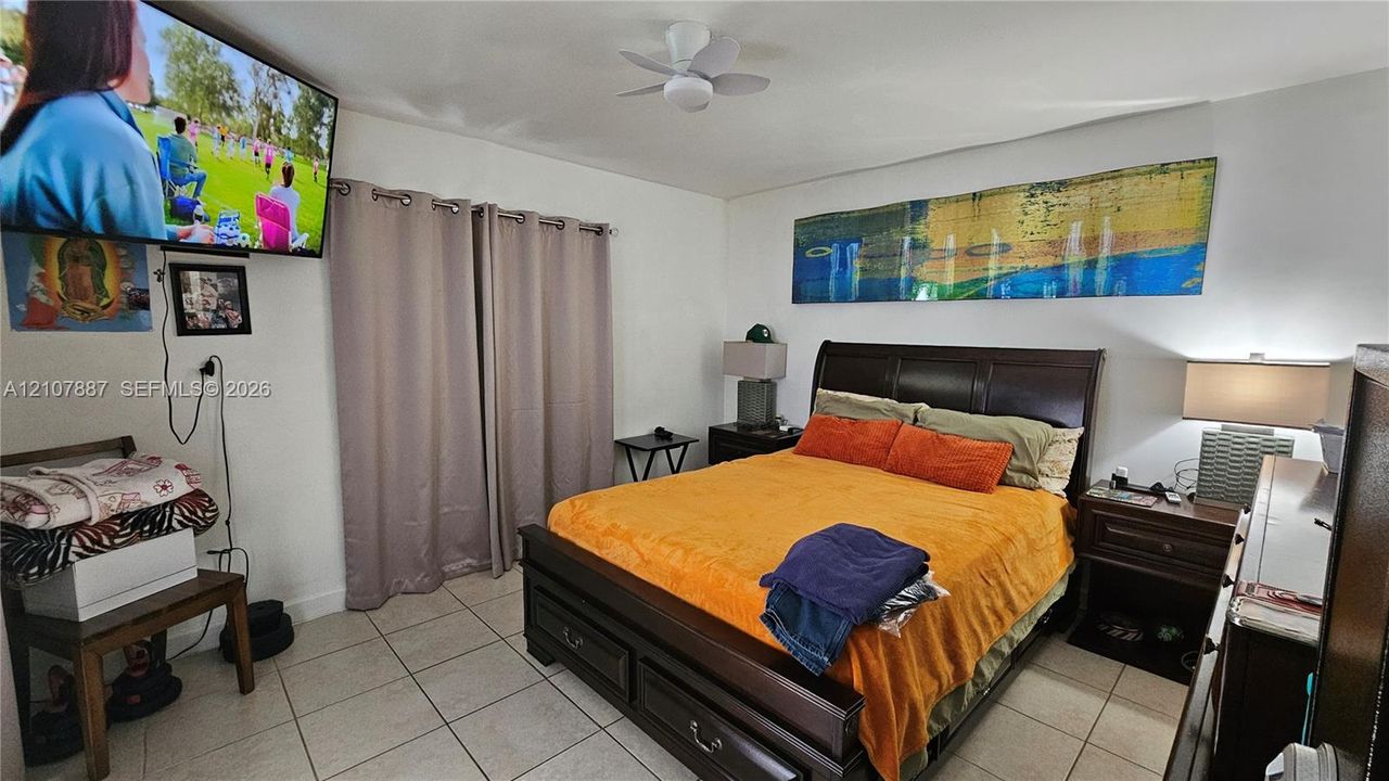 Neutral-toned tile flooring, ceiling fan, and window drapery