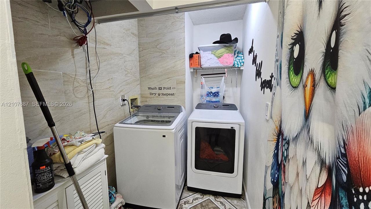 Laundry area featuring stone-finish wall tile, white cabinetry, and built-in wire shelving