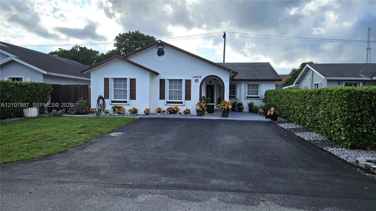 Single-story residence featuring a smooth stucco exterior, arched covered entryway, asphalt driveway, and shuttered windows